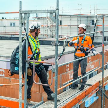 Zwei Industriekletterer stehen auf einem Gerüstbau gesichert mit ZARGES Absturzsicherung