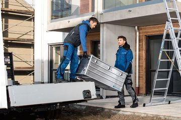 Zwei Handwerker arbeiten mit Gerüsten, Leitern und Kisten von Zarges.