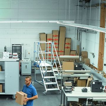 Federbodenwagen, K470 Universalkisten und fahrbare Podesttreppen werden von zwei Personen zur Erleichterung der Arbeit genutzt