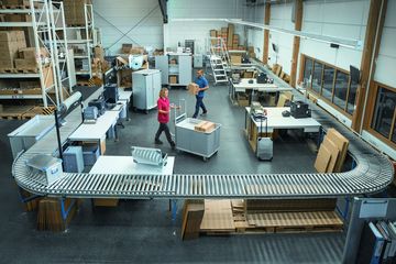 Federbodenwagen, K470 Universalkisten und fahrbare Podesttreppen werden von zwei Personen zur Erleichterung der Arbeit genutzt