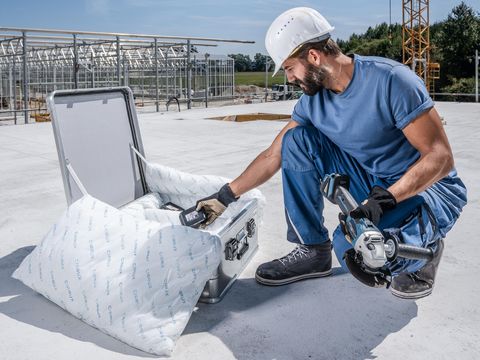 Ein Handwerker wechselt den Akku seines Winkelschleifers. Die Akkus werden in einem ZARGES Akku Safe gelagert und transportiert.