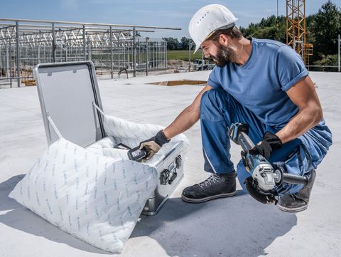Ein Handwerker wechselt den Akku seines Winkelschleifers. Die Akkus werden in einem ZARGES Akku Safe gelagert und transportiert.